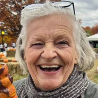 A woman laughing with a chocolate dessert skewer at a fall festival (illustrative photo)